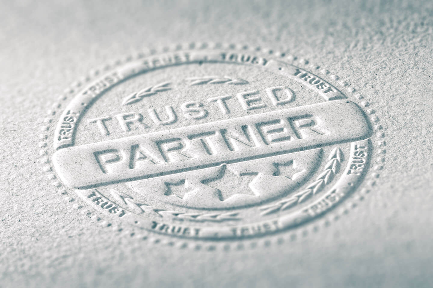 Ein Trusted-Partner-Siegel als Prägung auf weißem Papier in Detailaufnahme